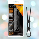 The Stay Hard Silicone Double Loop Adjustable Black Cock Ring, presented in a sleek white and black box with striking orange accents, is fully adjustable and made of stretchy silicone. It features a quick release mechanism, and the text at the bottom boldly declares, "Perform Like a Stud.